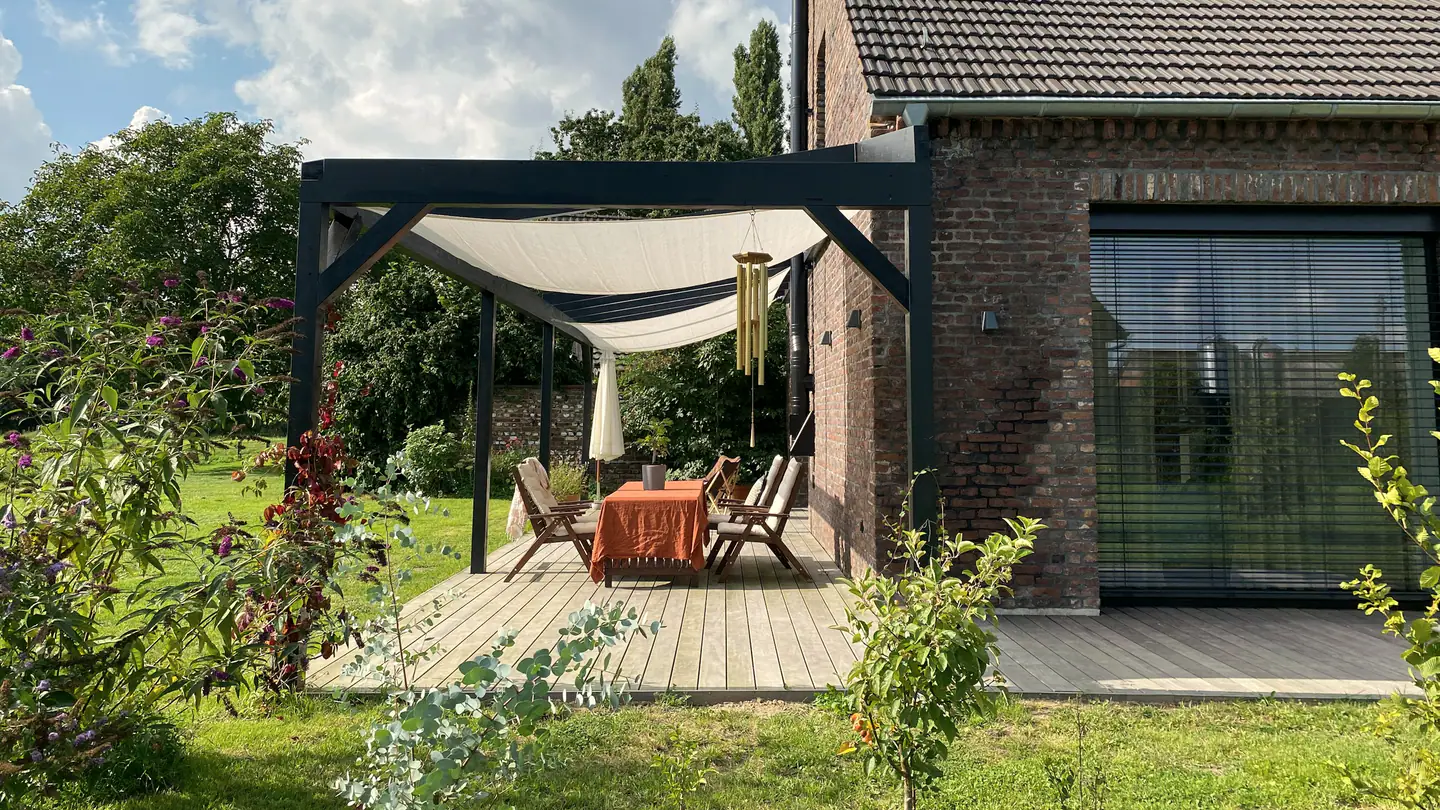 Gartenseite des Klinkerhauses mit Pergola, Sonnensegel und Holzterrasse