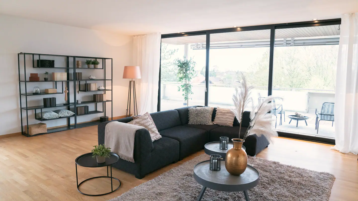 Wohnzimmer mit Ecksofa und raumhoher Glasfront zur Loggia