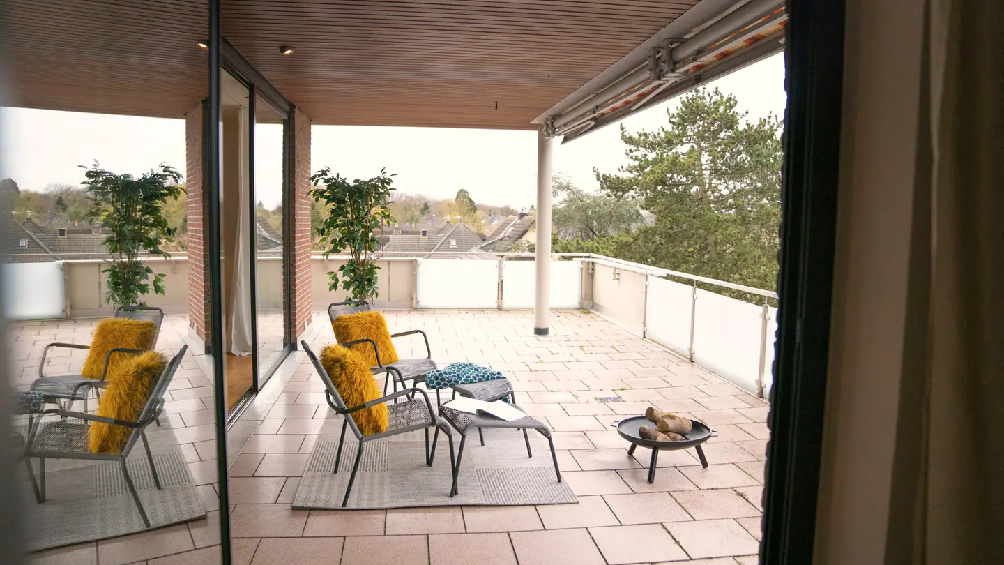Überdachte Loggia mit zwei Liegestühlen und Blick in die Bäume