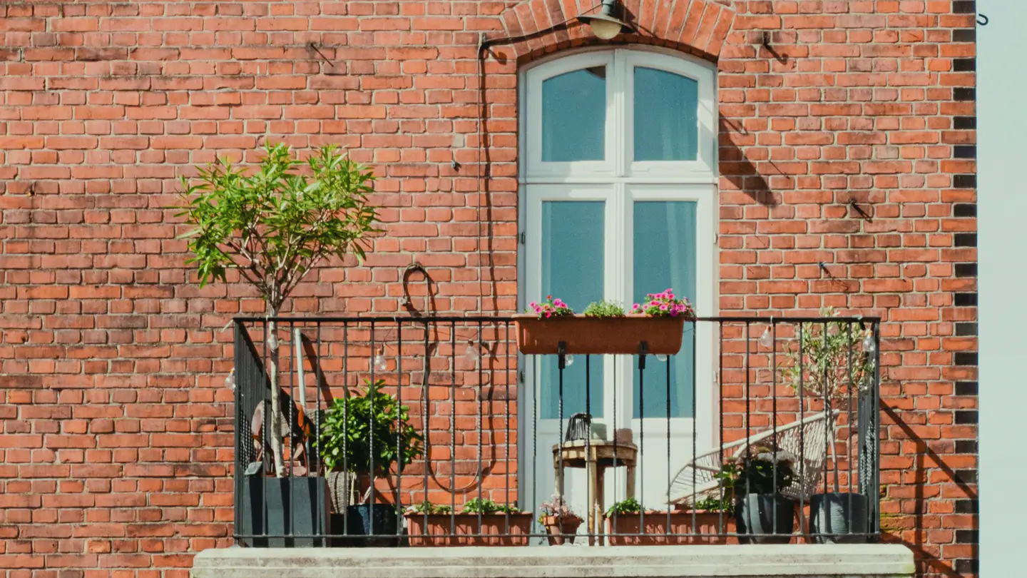 Kleiner Balkon mit Pflanzen an einer Backsteinfassade