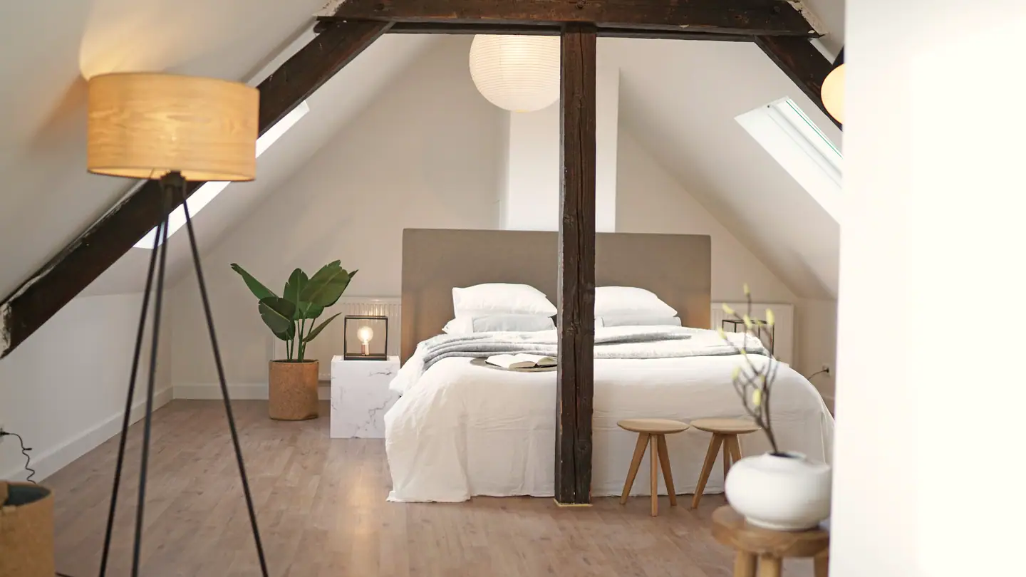 Schlafzimmer unter offenen Dachbalken mit zwei Dachfenstern
