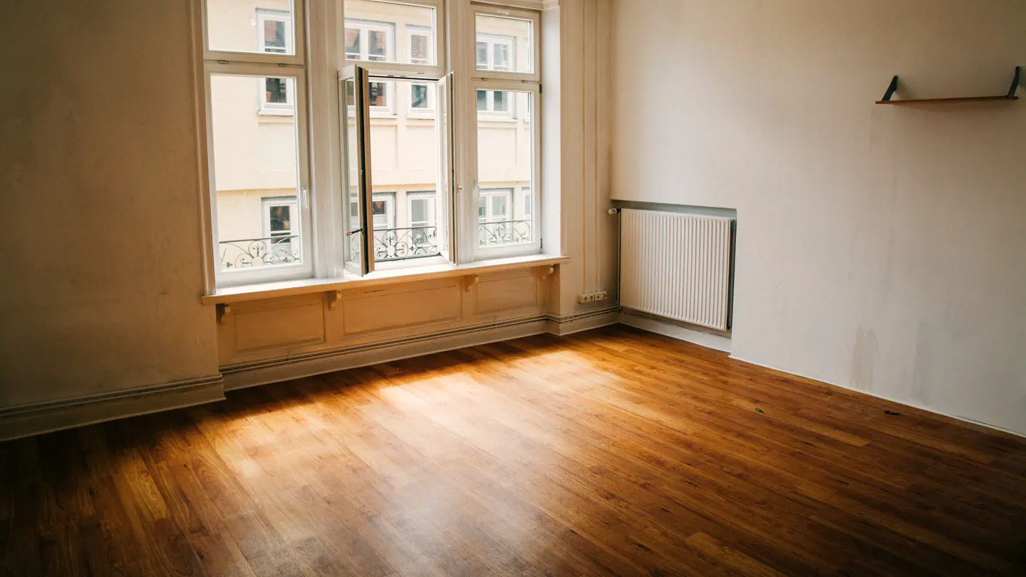 Leeres Zimmer, Sonne auf dem Holzboden, drei hohe Fenster