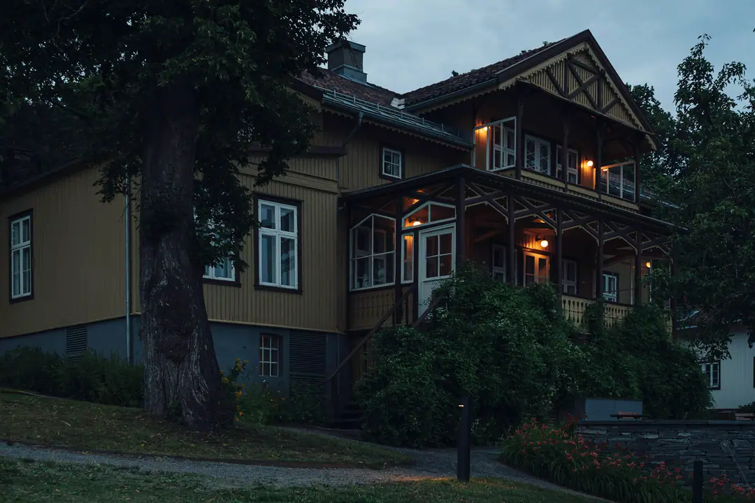 Holzhaus in der Dämmerung, warmes Licht in den Fenstern